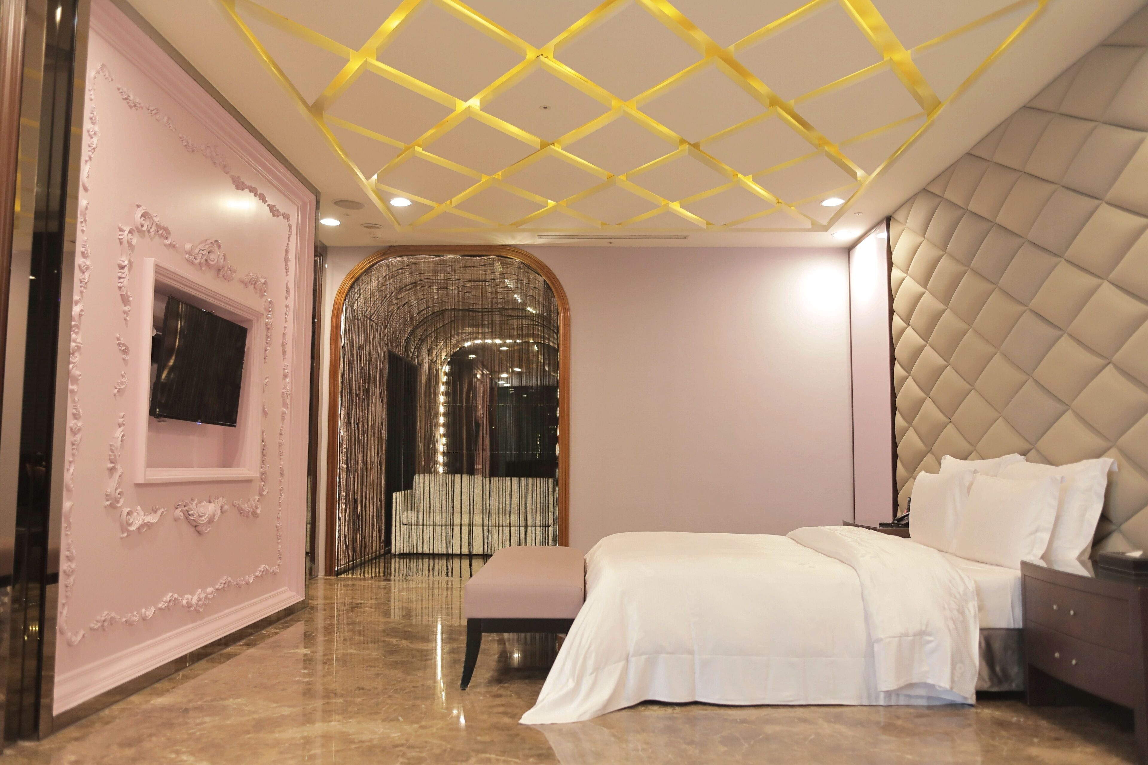 A modern bedroom with a large bed, a vanity, and a decorative mirror.