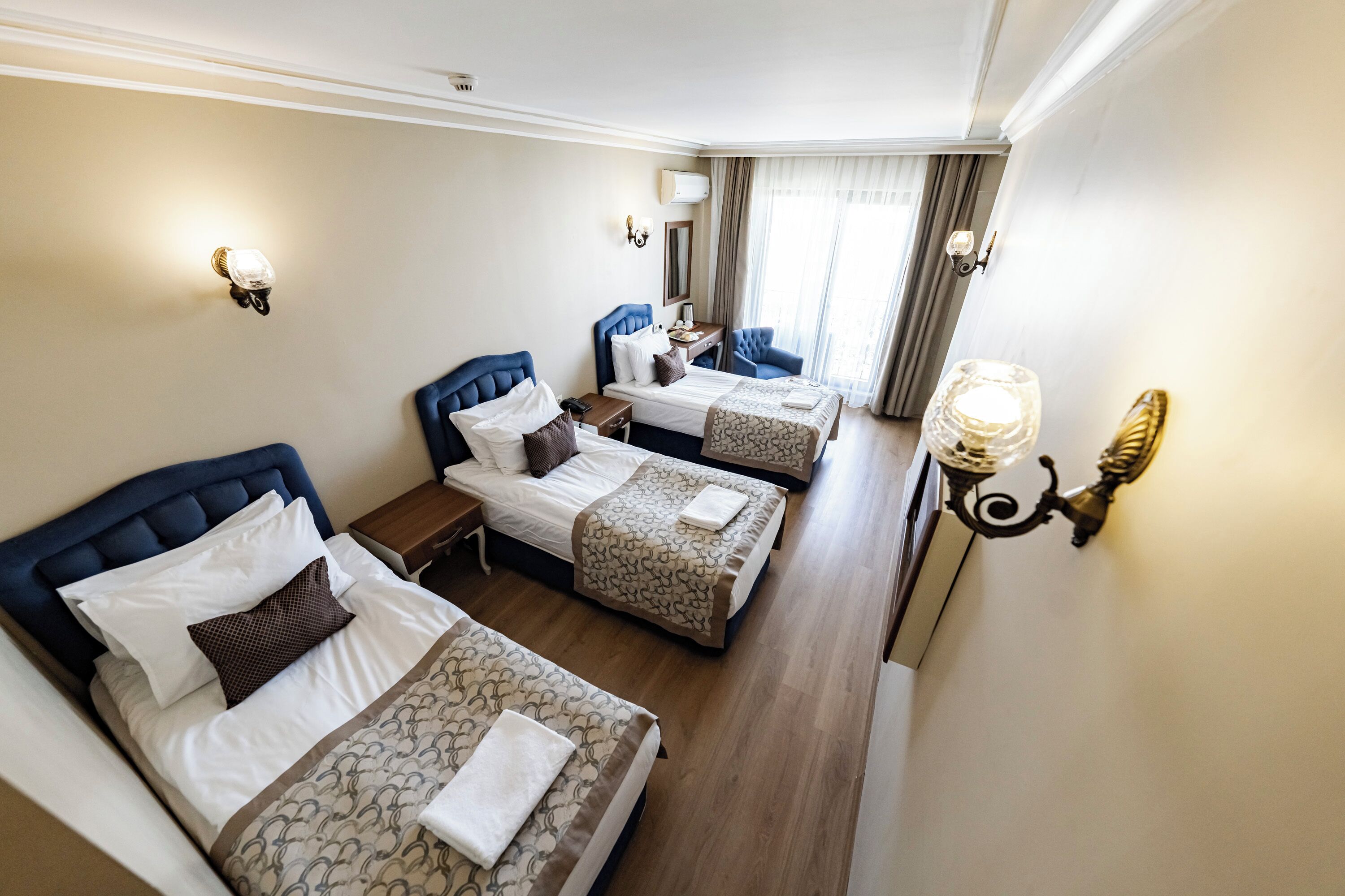 A hotel room with two beds, a desk, and a chair.