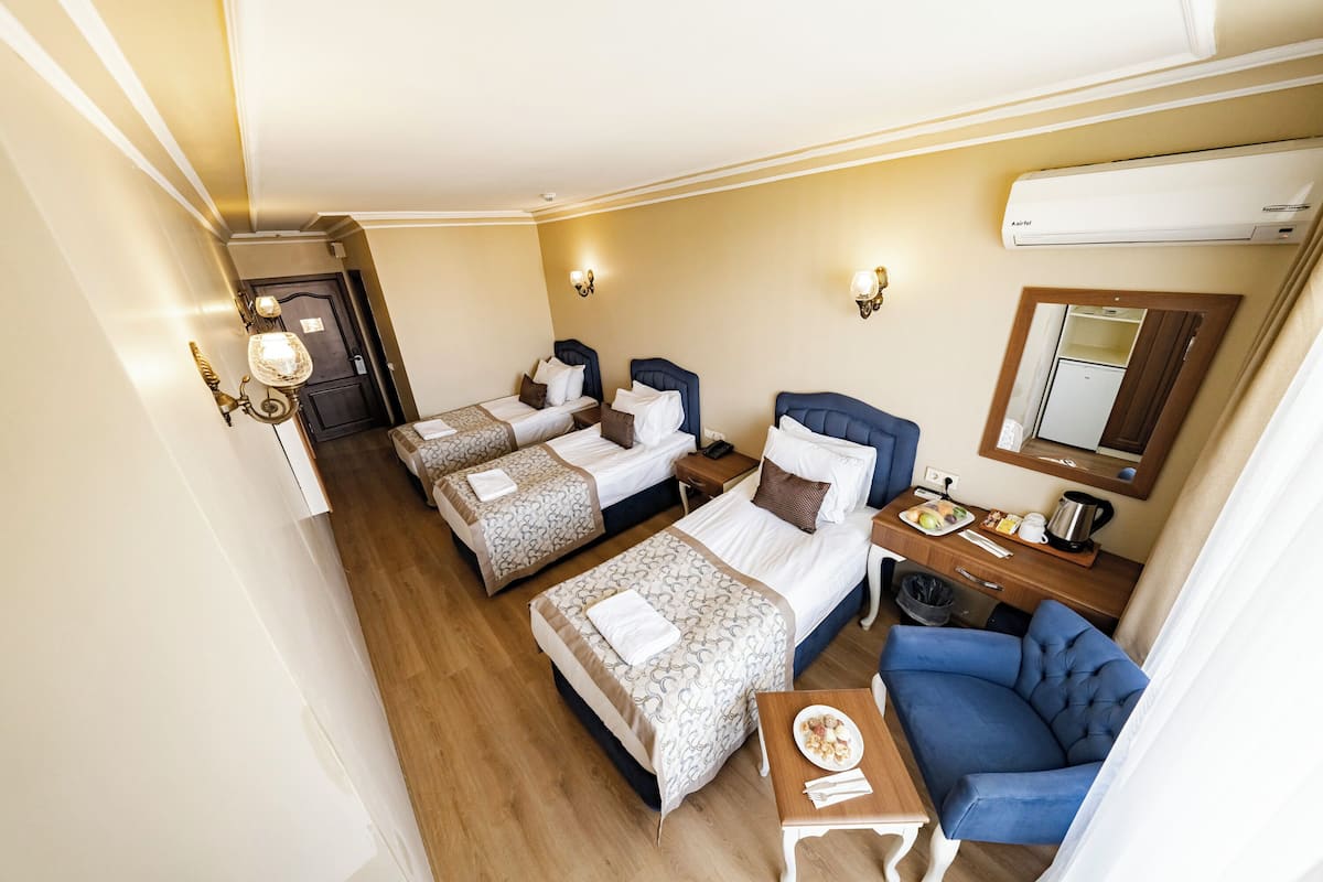 Una habitació d'hotel amb dos llits, un escriptori amb una cadira, una taula petita amb un plat de menjar i un mirall a la paret.