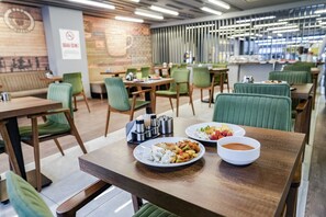 Un restaurante con mesas de madera y sillas tapizadas en verde.