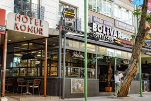 Un hotel llamado "HOTEL KONUR" con una cafetería llamada "BOLIVAR COFFEE SHOP" en la fachada.