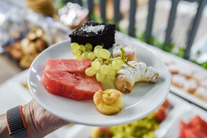 Un plato con sandía, uvas, un postre de chocolate y un pastel.