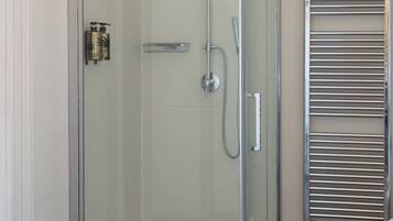 A glass-enclosed shower area with a handheld showerhead, a wall-mounted towel rack, and a glass door.