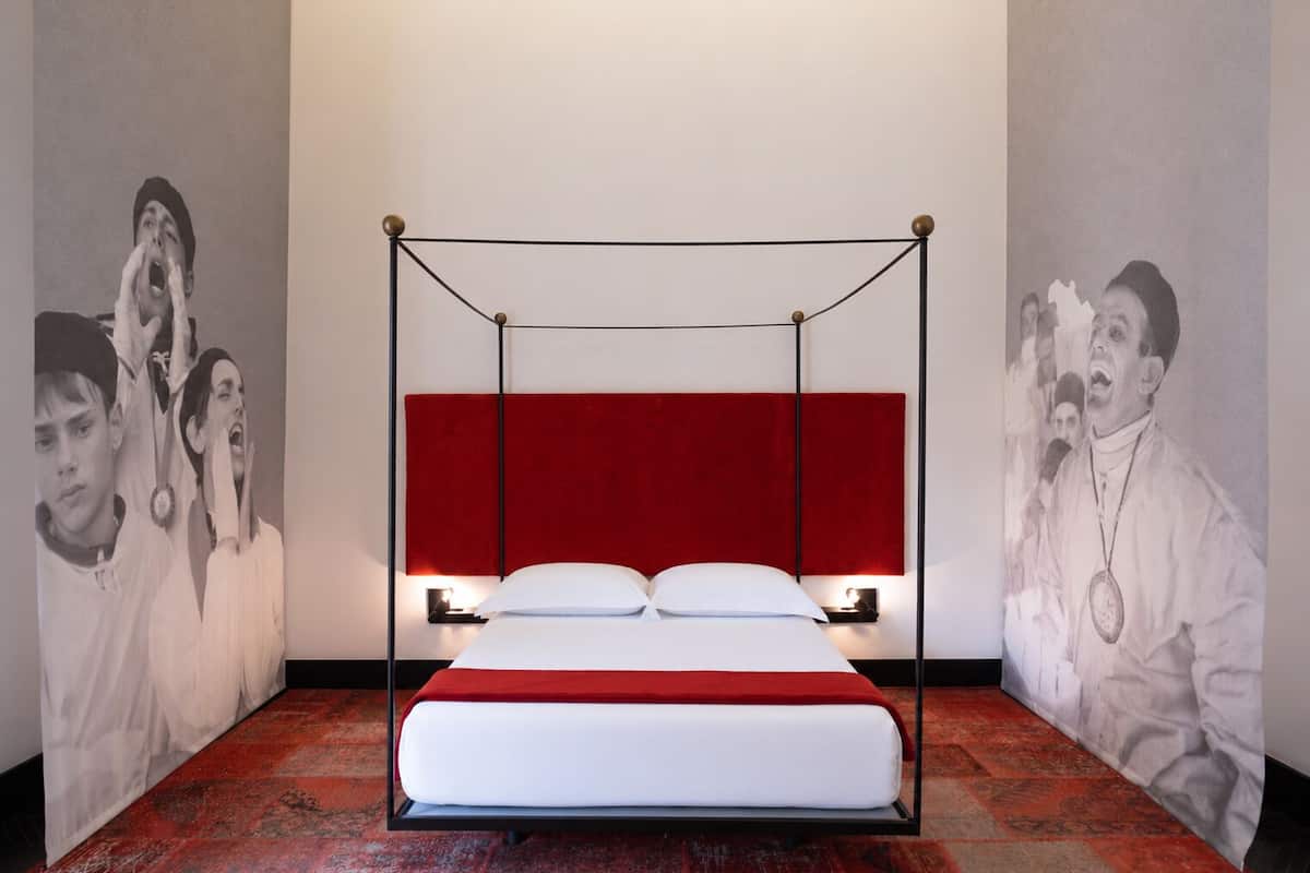 Ein Bett mit einem roten Kopfteil, weißer Bettwäsche und einem roten Teppich.