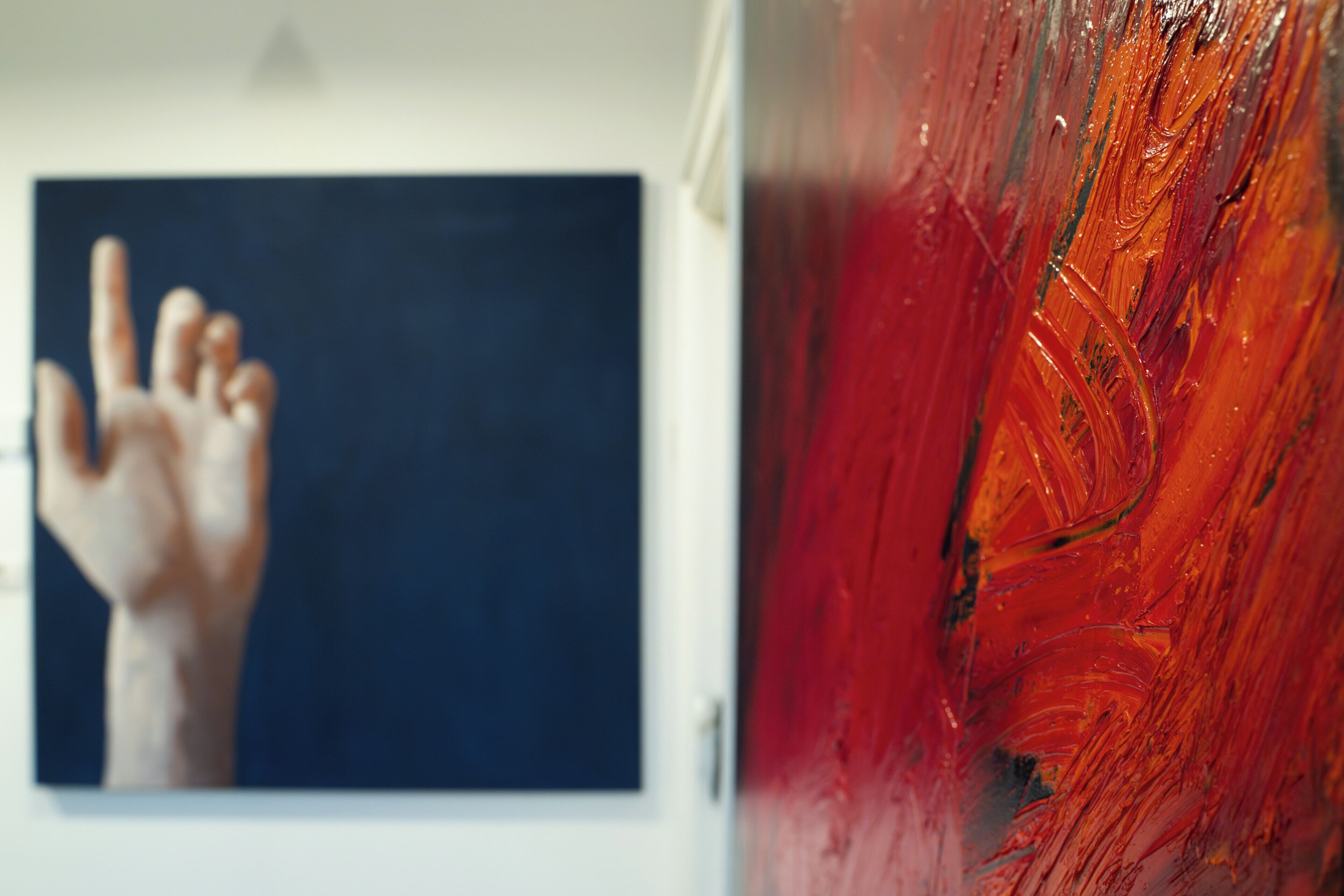 Una mano se extiende hacia una obra de arte enmarcada en azul oscuro sobre una pared blanca.