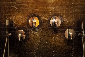 Un baño con un diseño de azulejos hexagonales, tres espejos redondos y un cabezal de ducha manual.