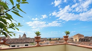 Una terrazza sul tetto con sedie bianche, un tavolino e piante in vaso.