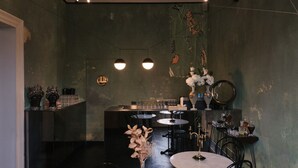 Eine Bar mit Theke, zwei Pendelleuchten, einem runden Tisch und einem Spiegel.