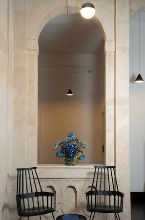 A stone archway with two black chairs and a blue vase. - Asmundo di Gisira (Catania)