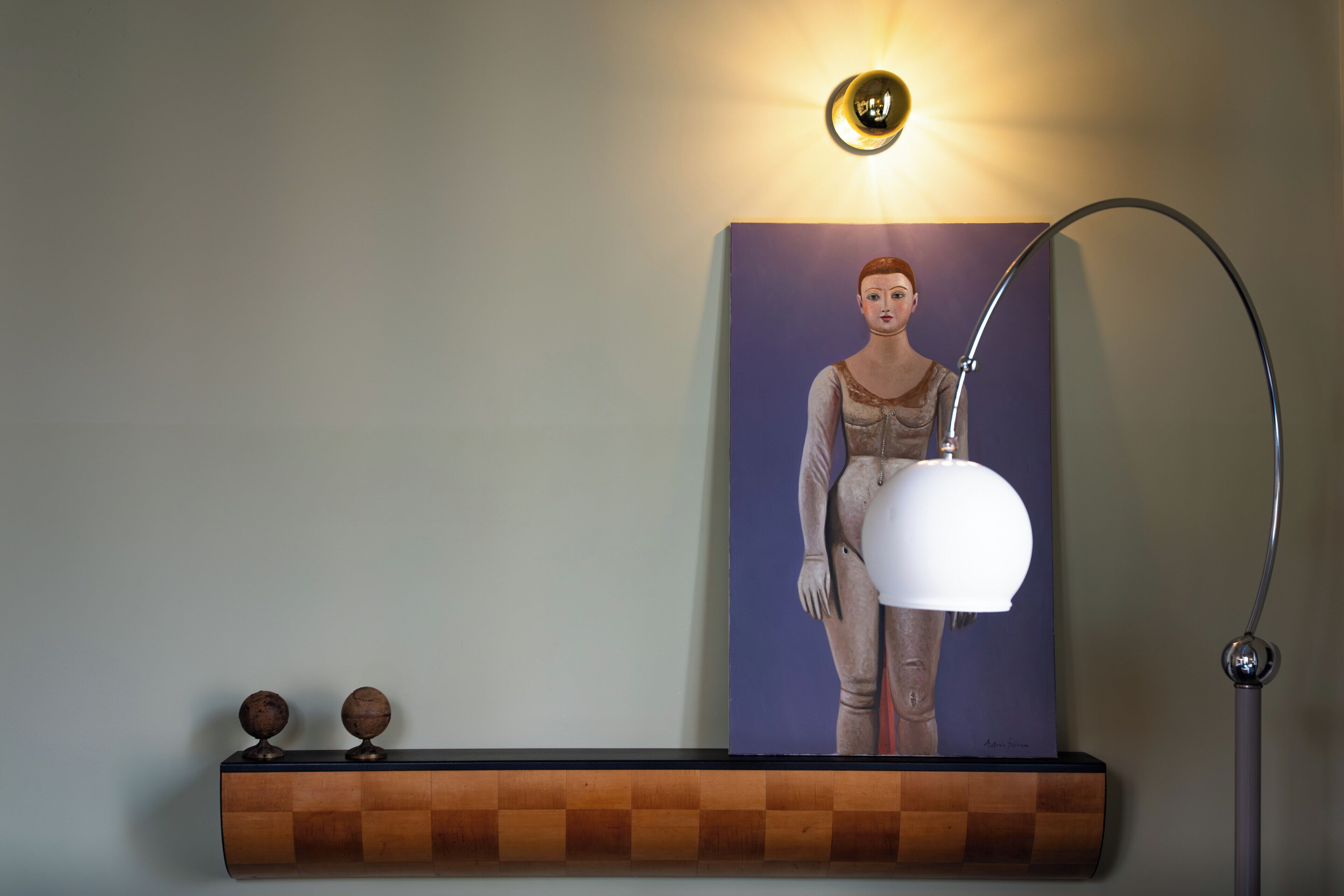 Ein Wandbild mit einer Figur, eine Wandleuchte und eine Stehlampe.