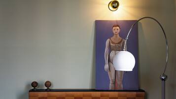 Ein Wandbild mit einer Figur, eine Wandleuchte und eine Stehlampe.