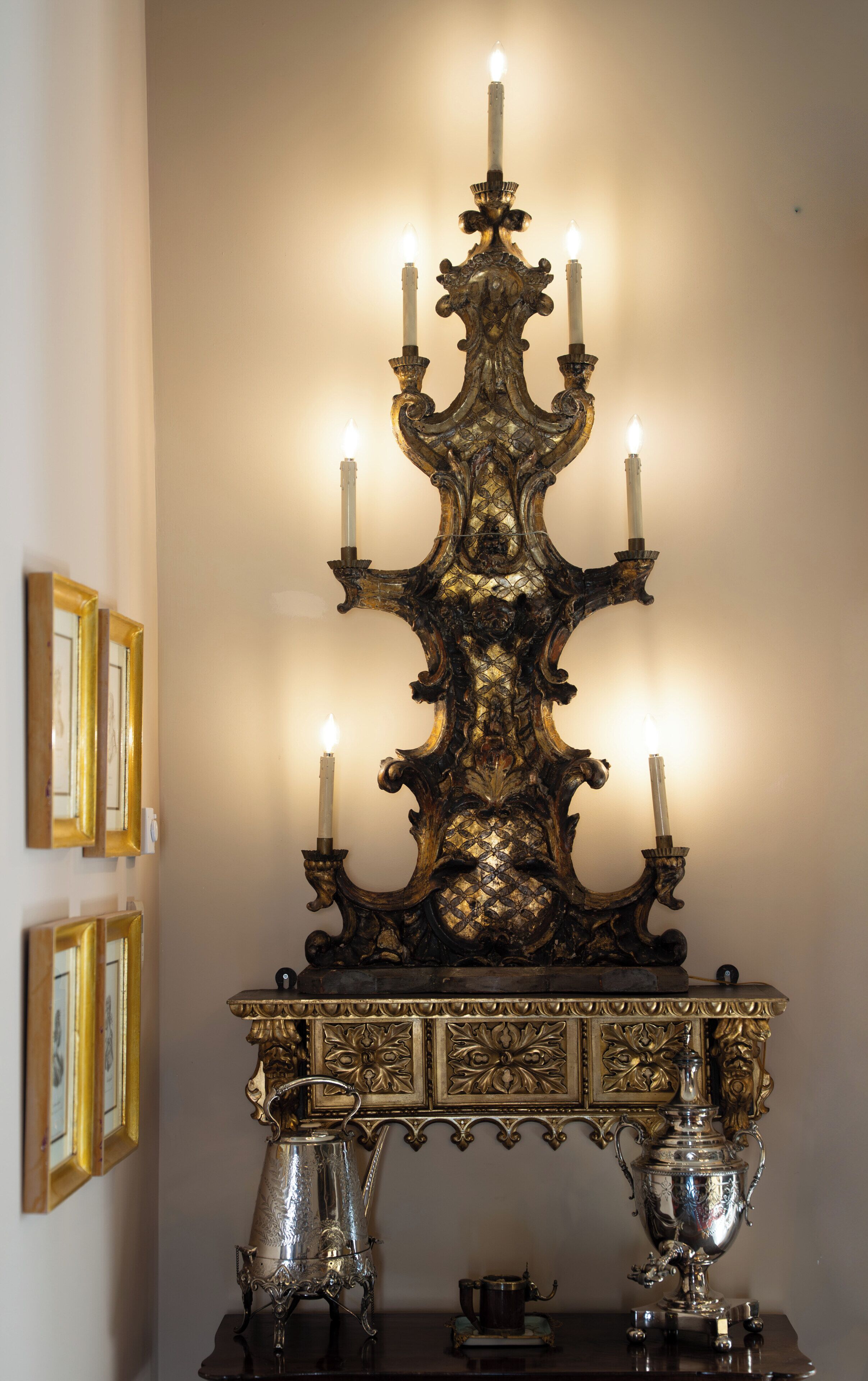 An ornate candelabra with multiple candles, a decorative mirror, and a silver teapot on a wooden table.