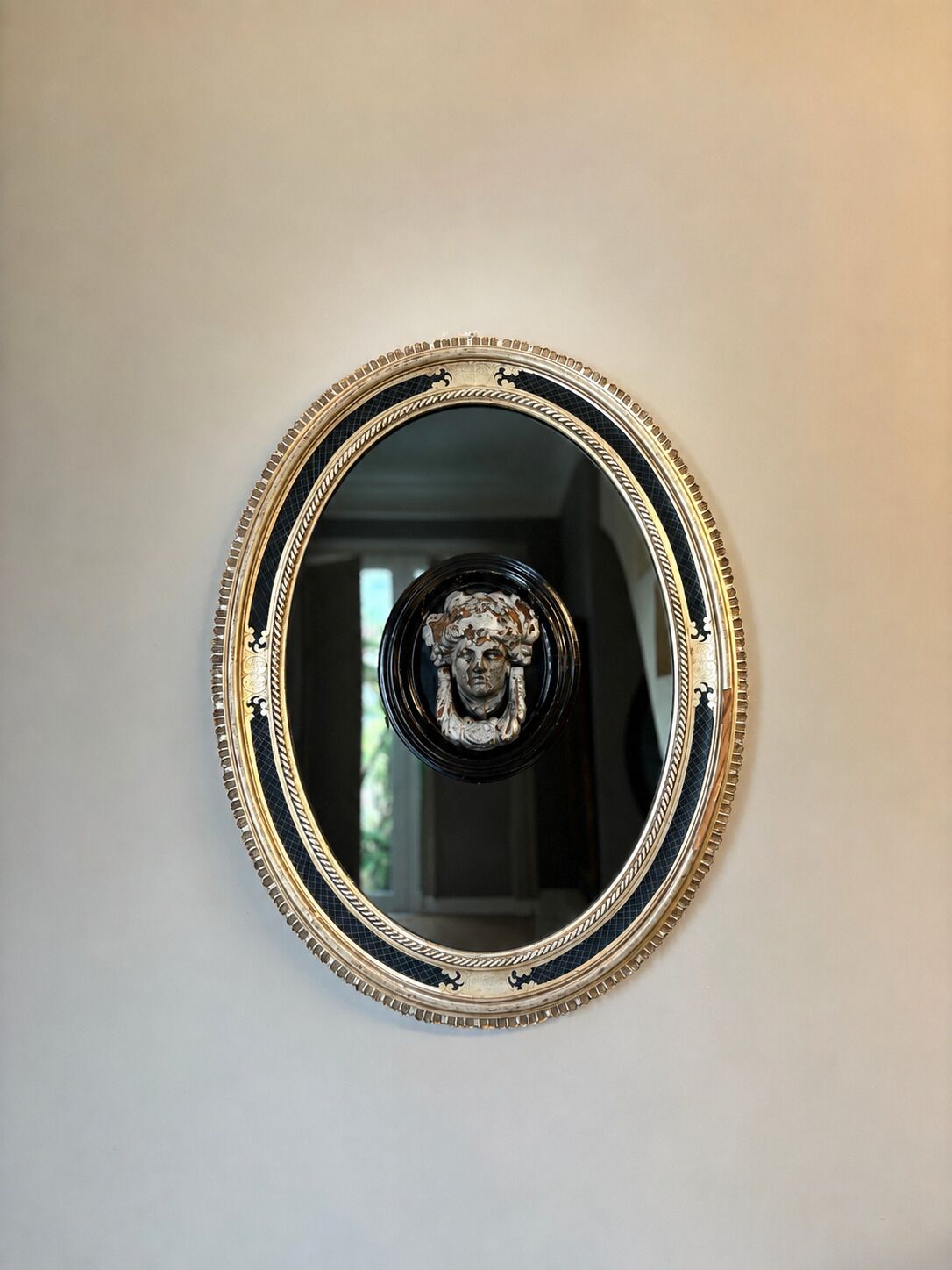 A round mirror with a decorative frame mounted on a wall.