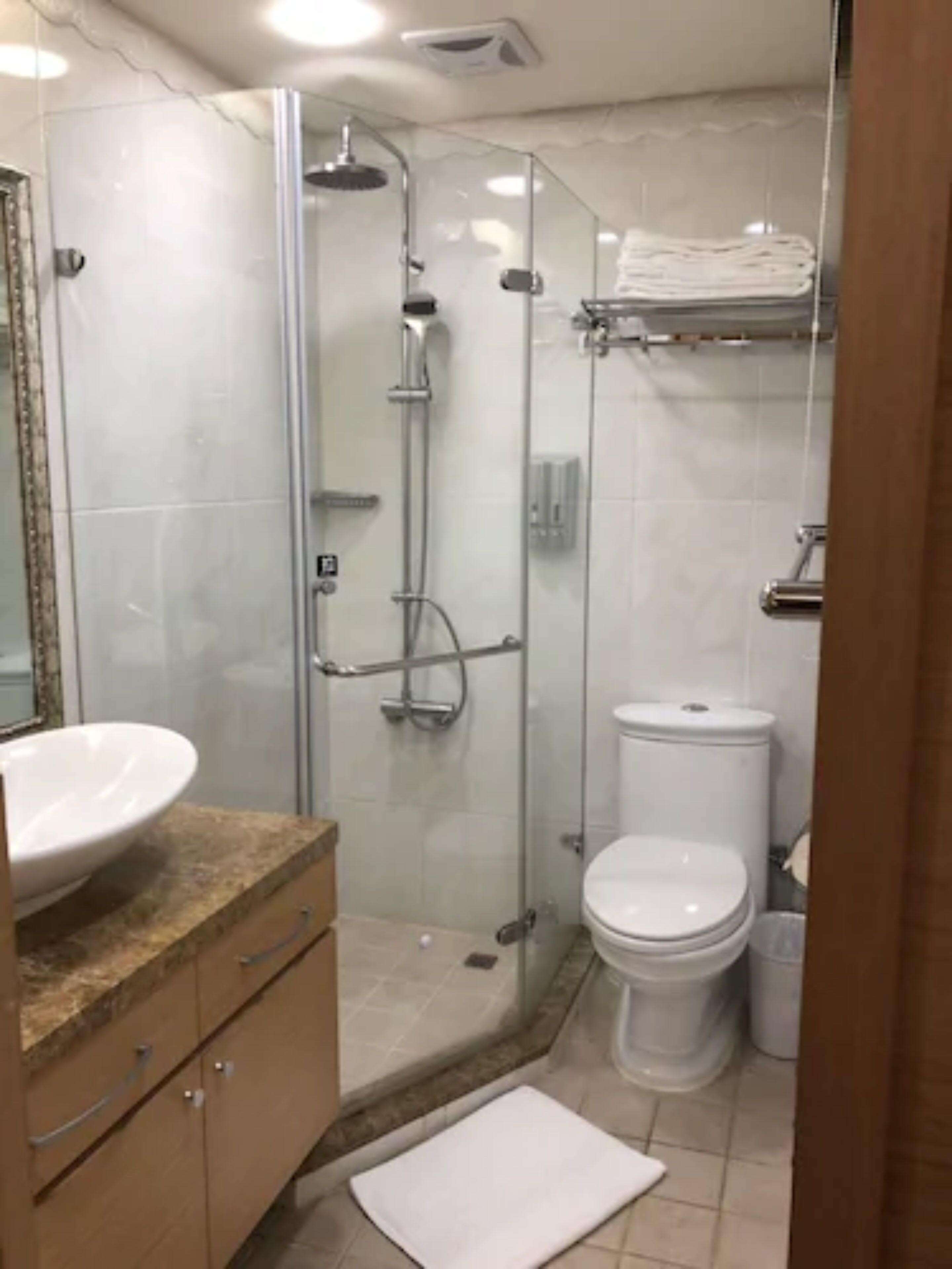 A bathroom with a glass-enclosed shower, a white sink, and a toilet.
