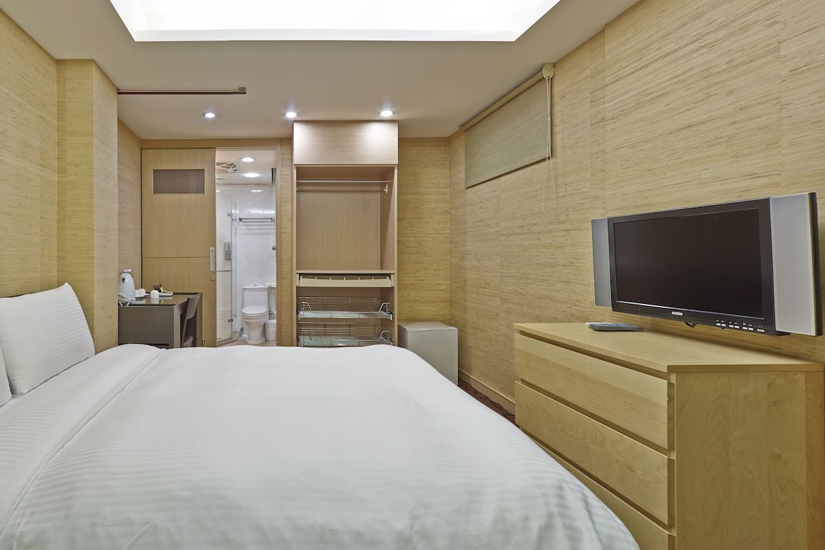 Une chambre d’hôtel avec un grand lit, une télévision, une armoire et un dressing.