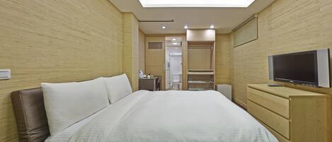 A hotel room with a large bed, a TV, a wardrobe, and a walk-in closet.