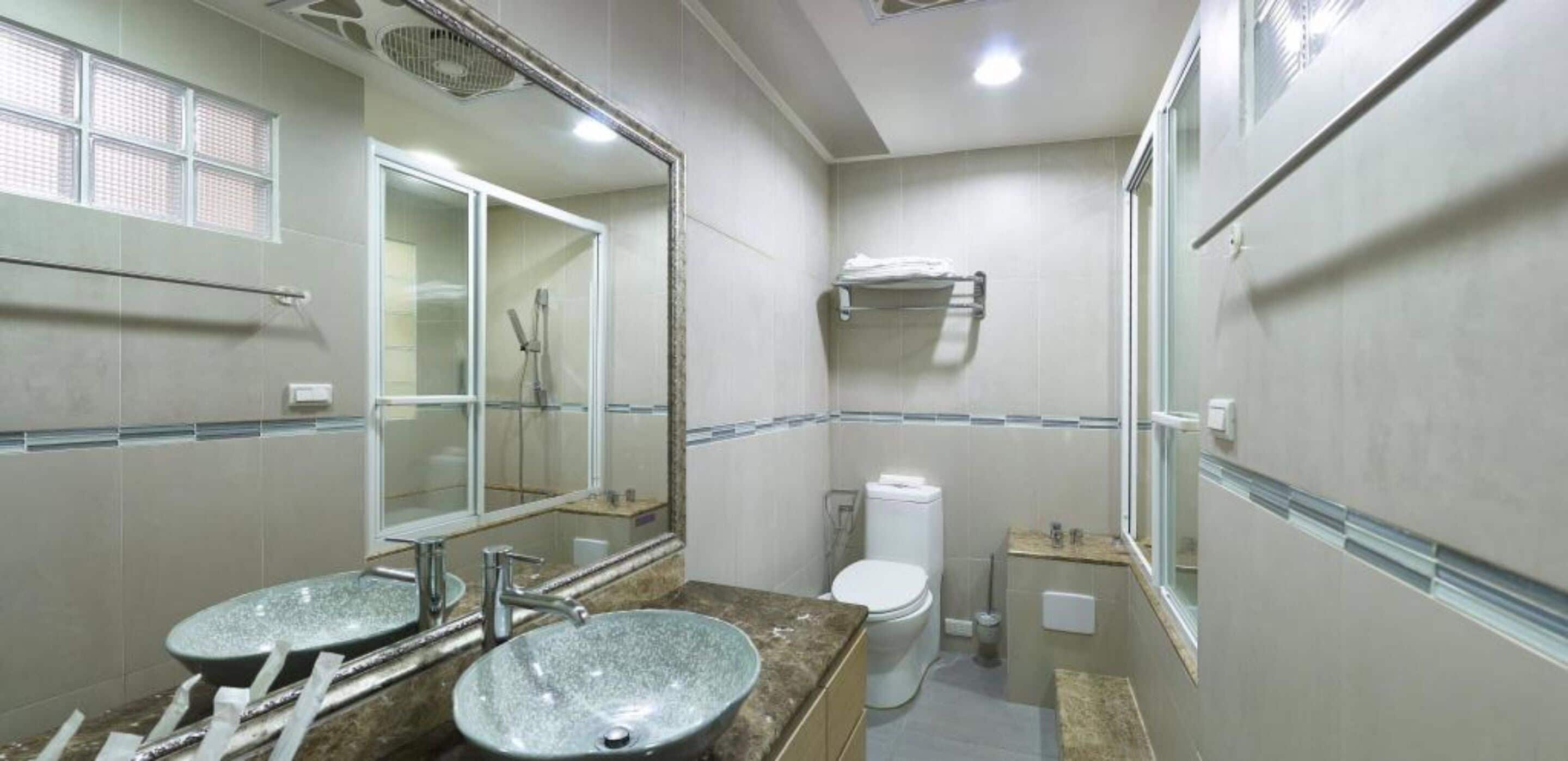 Une salle de bain avec deux lavabos, des toilettes et une douche.