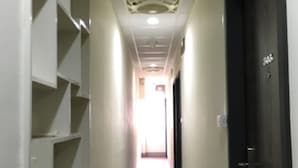 A narrow hallway with white walls, a wooden floor, and a dark door at the end. Shelves are mounted on the left wall. - West 59 Inn  (Taipei)