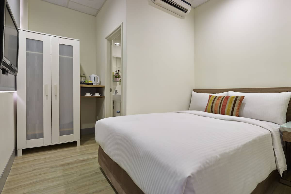 Une chambre d’hôtel comprenant un lit, une armoire, une petite kitchenette et une salle de bain.