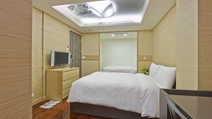 A modern hotel room with a bed, a TV on a wooden dresser, a ceiling fan, and a skylight. - West 59 Inn  (Taipei)