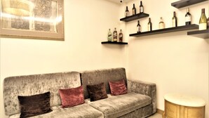 A living room with a grey sofa, two cushions, a small round table, and wine bottles on shelves. - West 59 Inn  (Taipei)