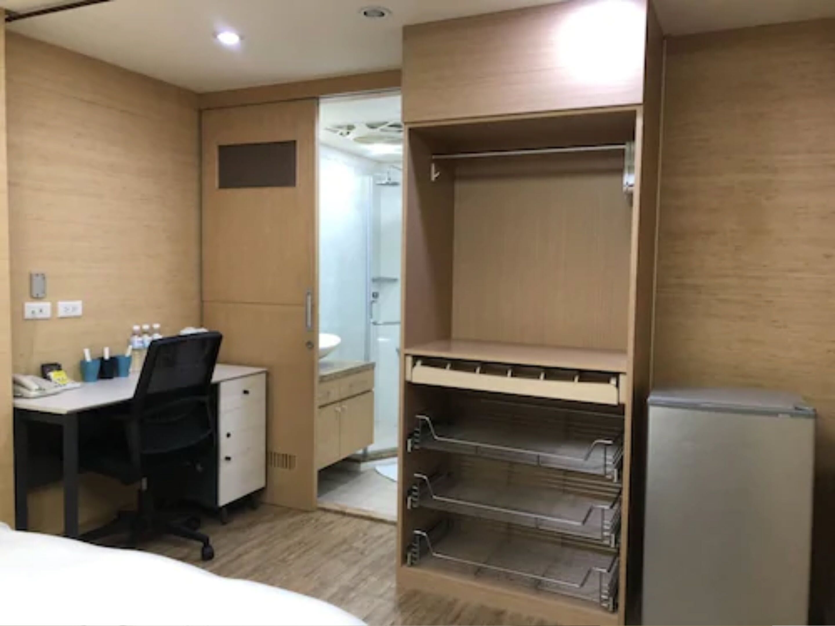 Habitación de hotel con escritorio, silla y armario con estantes.
