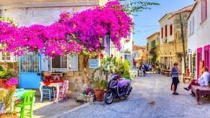 Una calle empedrada con un café, mesas al aire libre y una motocicleta estacionada al lado.