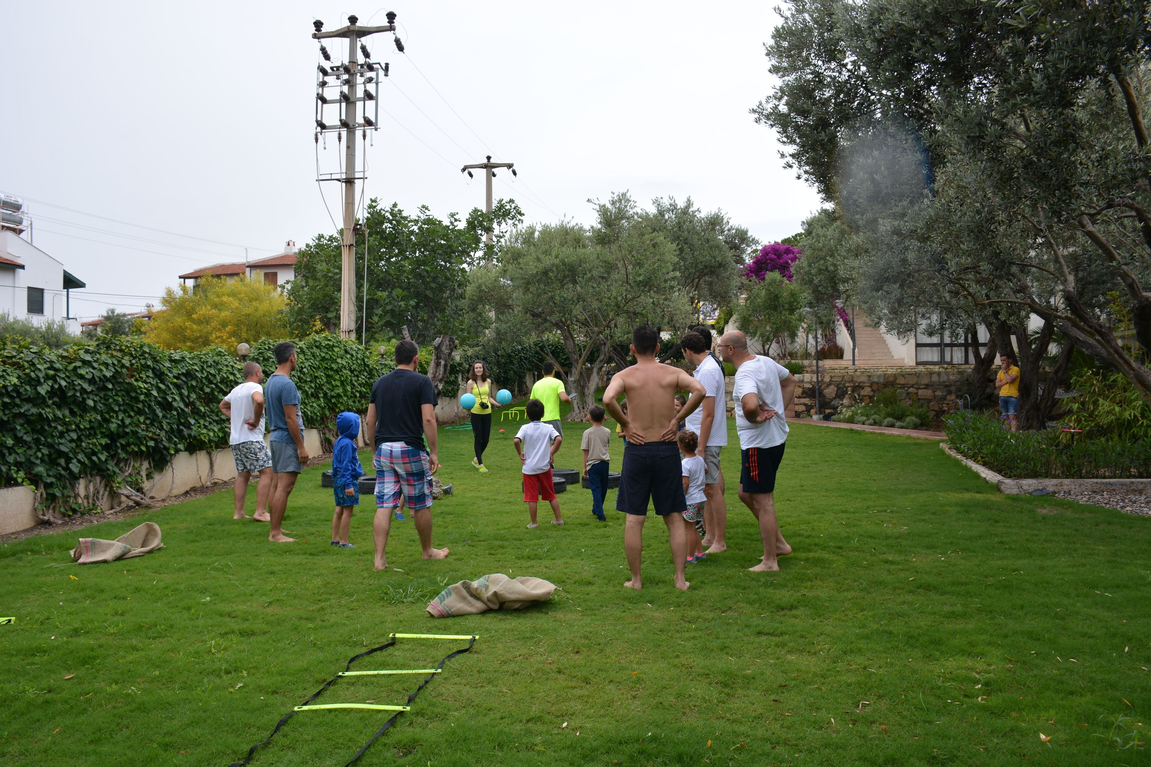 A group of people standing on a grassy area with a stone wall and trees in the background.