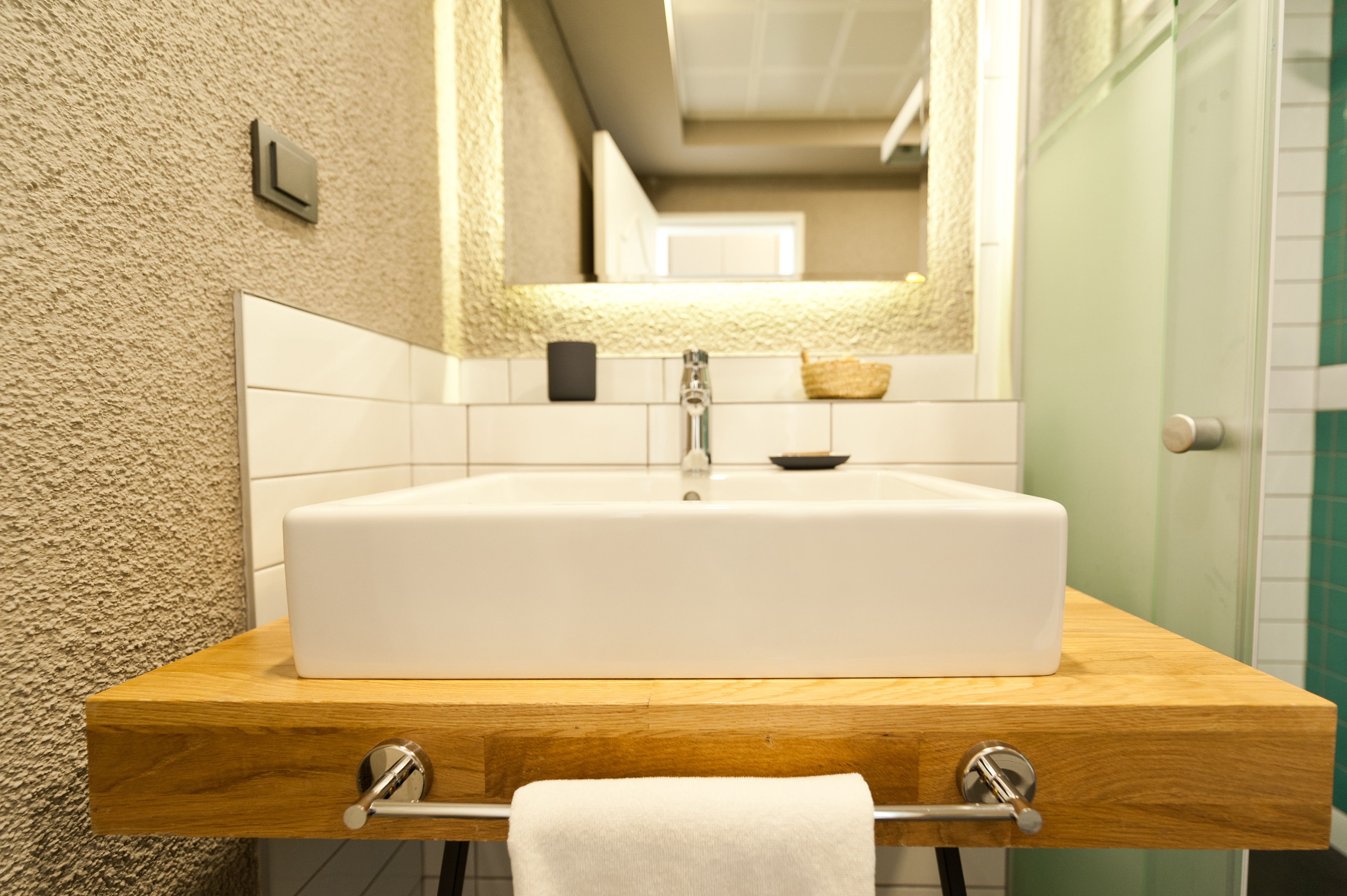A bathroom with a large white sink, wooden countertop, and a towel rack.