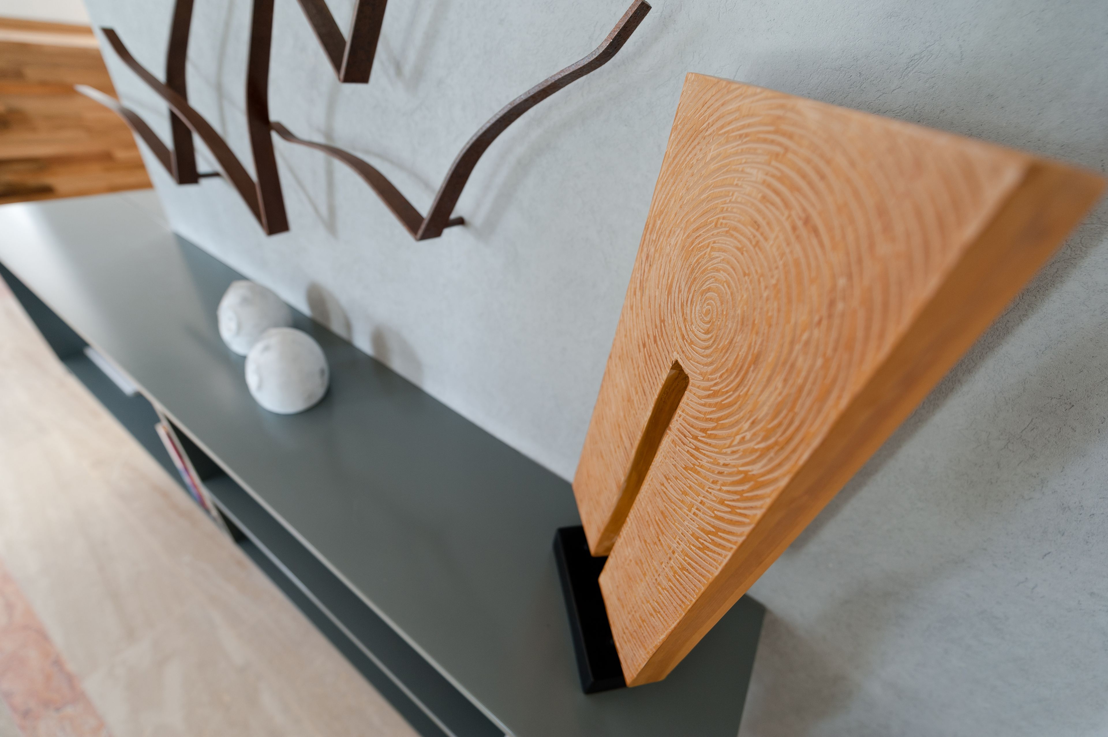 Un dettaglio di un'opera d'arte a parete, con un pannello di legno strutturato e uno sfondo bianco.