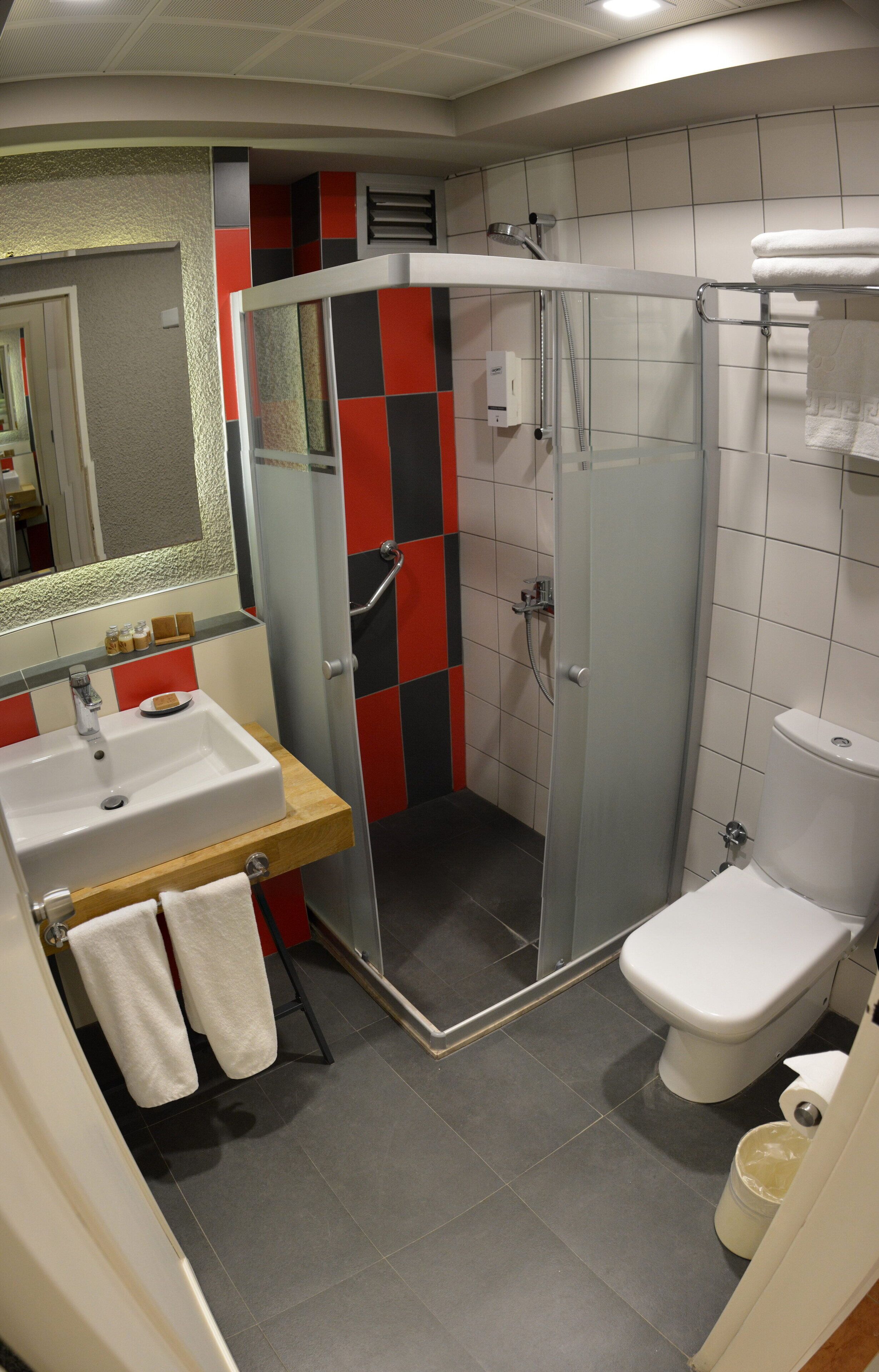 Un baño con ducha de vidrio, lavamanos e inodoro.