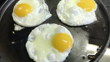 Tre stekt ägg, stekta med äggulan uppåt, i en svart stekpanna.