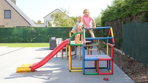 Un parque infantil con un tobogán, estructuras para escalar y un banco.