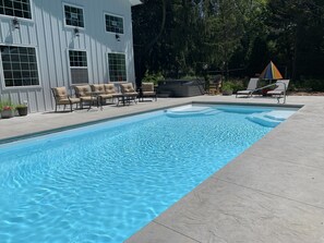 Una piscina al aire libre, sombrillas, sillones reclinables de piscina