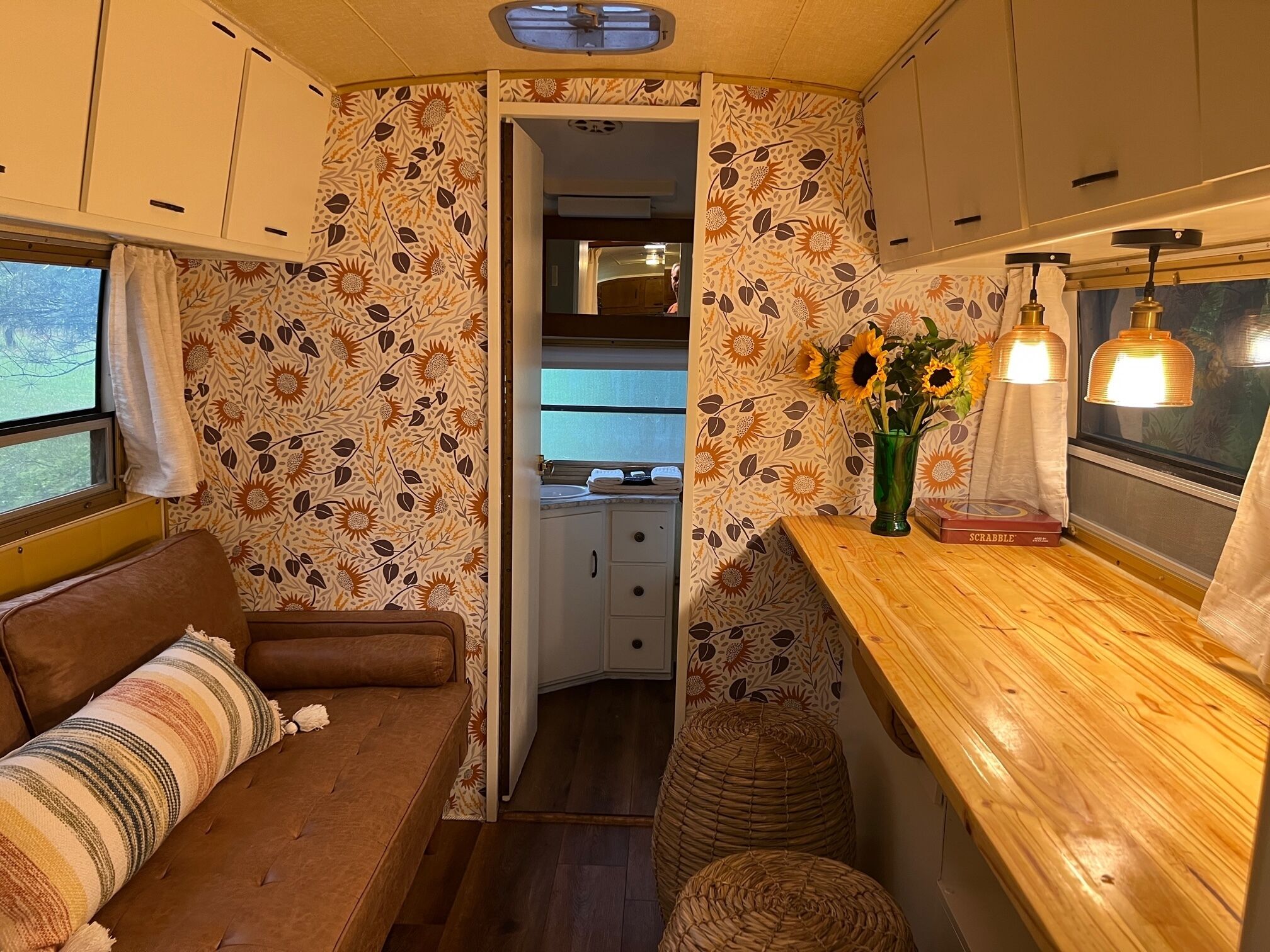 A cozy RV interior with a kitchenette, a dining area with a wooden table, and a seating area with a sofa.