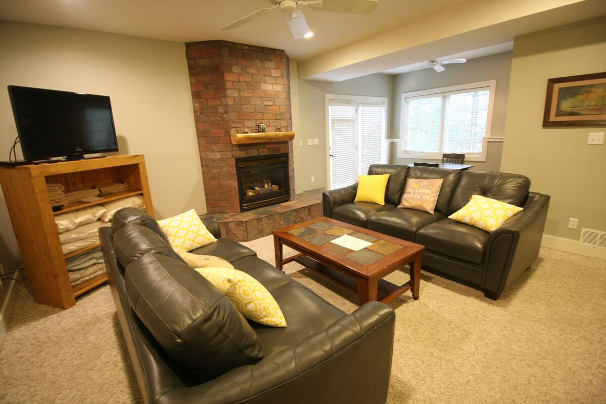 A living room with a fireplace, leather sofas, and a television.