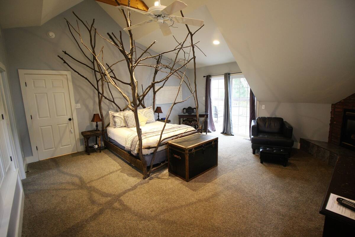 A bedroom with a bed, a wooden chest, a chair, and a ceiling fan.