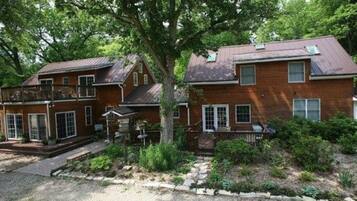 A two-story brick house with a front porch, a covered patio, and a gravel driveway.