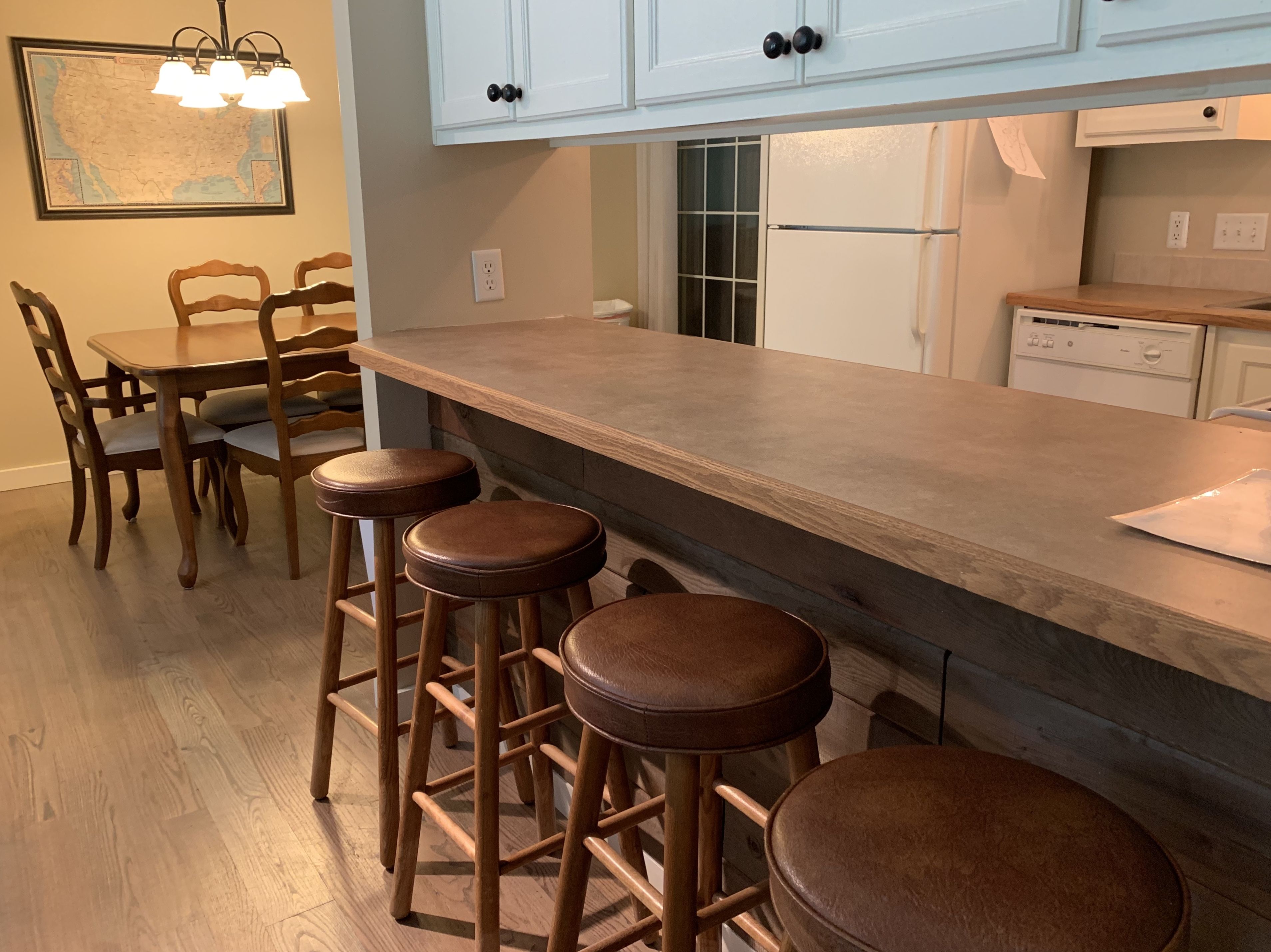 Una cocina con taburetes de madera, una mesa de comedor y sillas.
