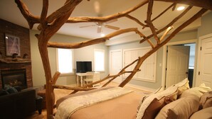 A bedroom with a large bed, a fireplace, and a TV in the background. - Goldberry Woods (Union Pier)