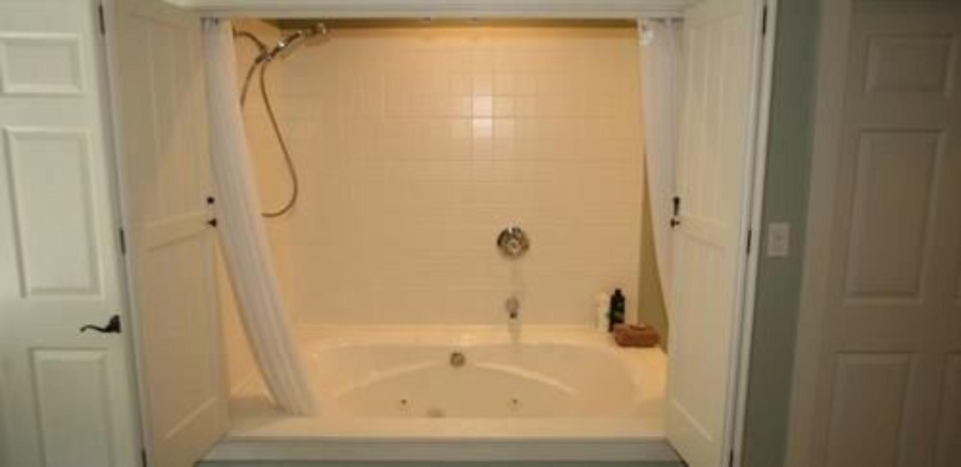 A bathroom with a bathtub, a shower curtain, and a toilet.