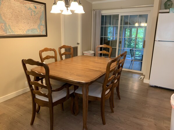 Un comedor con una mesa y sillas de madera, un mapa en la pared y vistas a través de un ventanal.