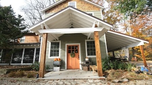A house with a porch, a front door, and a small garden area with plants and pumpkins. - Goldberry Woods (Union Pier)