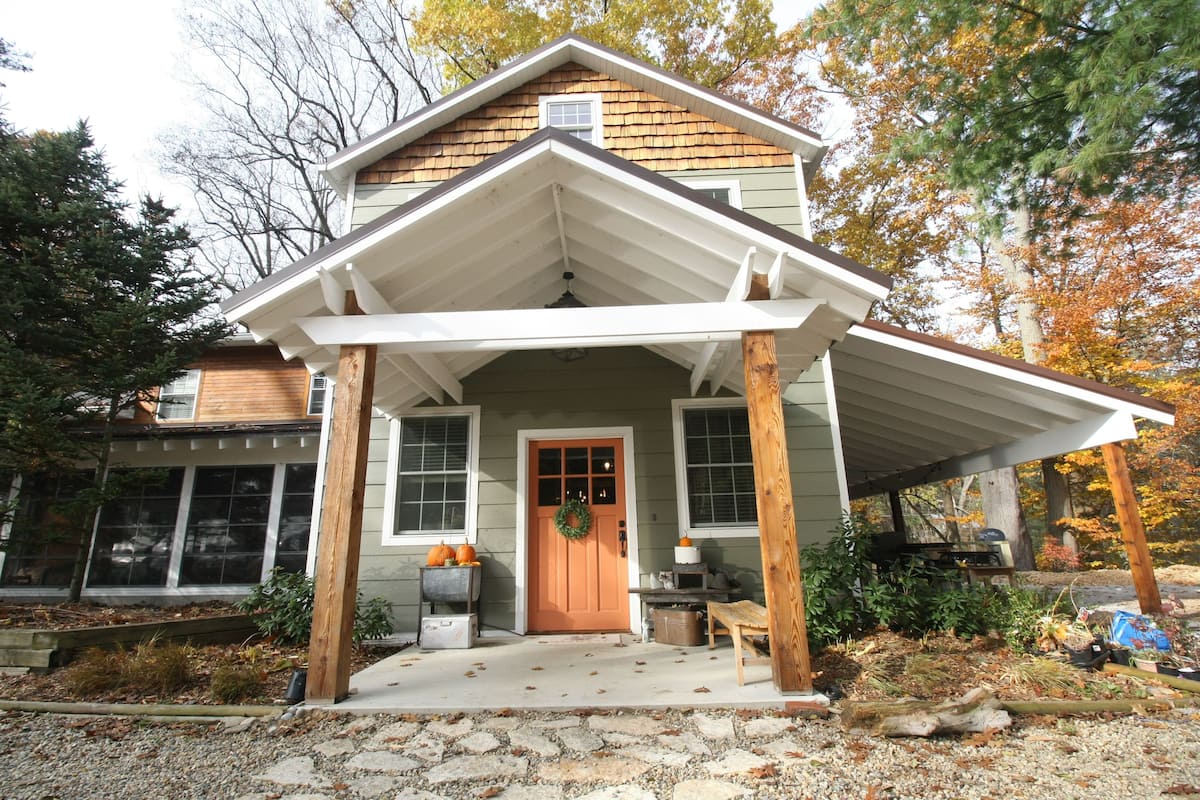 A house with a porch, a front door, and a small garden area with plants and pumpkins.
