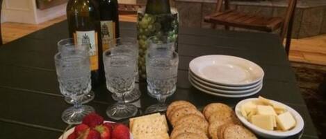 A table with wine bottles, glasses, strawberries, crackers, and a bowl of cheese.