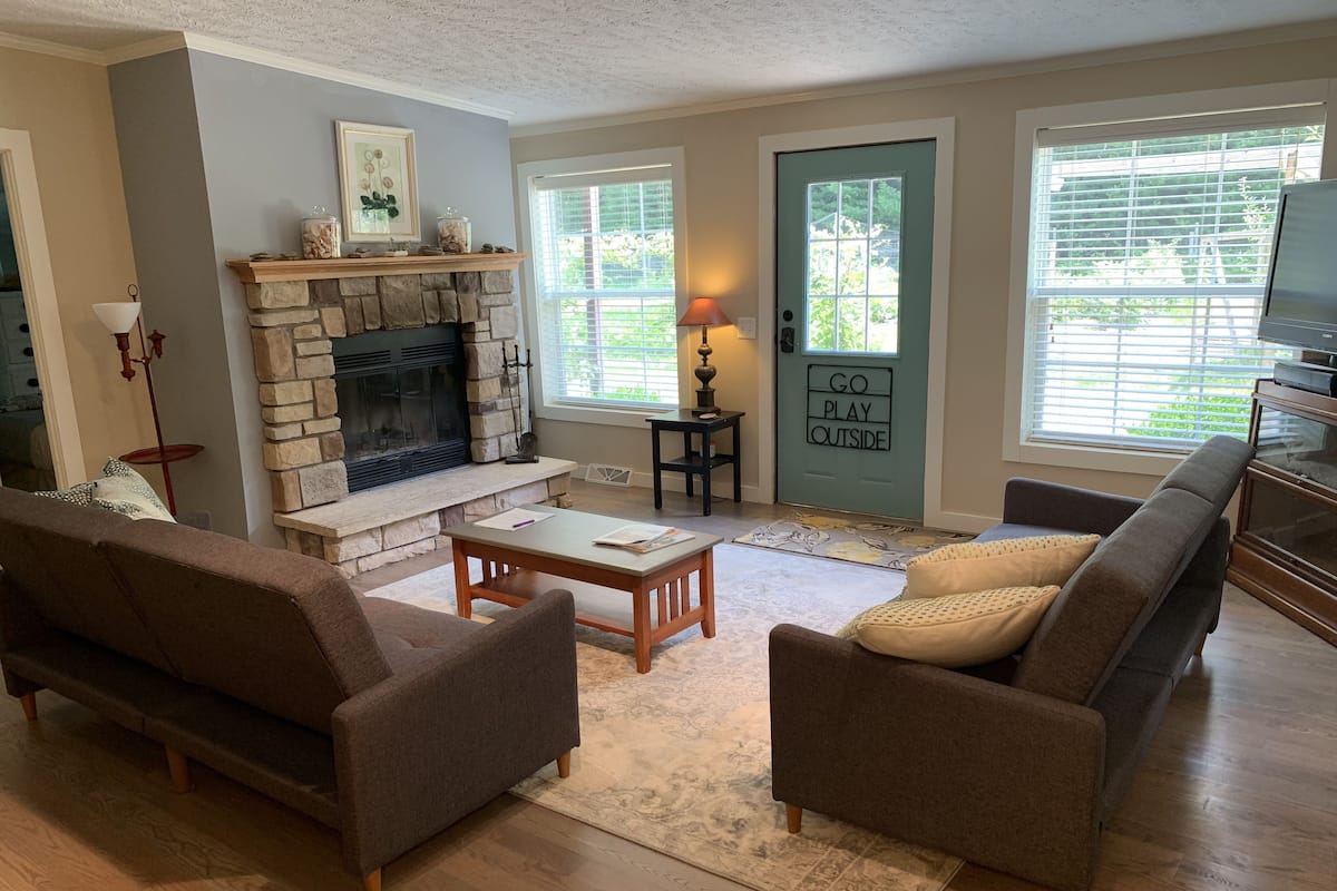 A living room with a stone fireplace, two sofas, a coffee table, and a television.