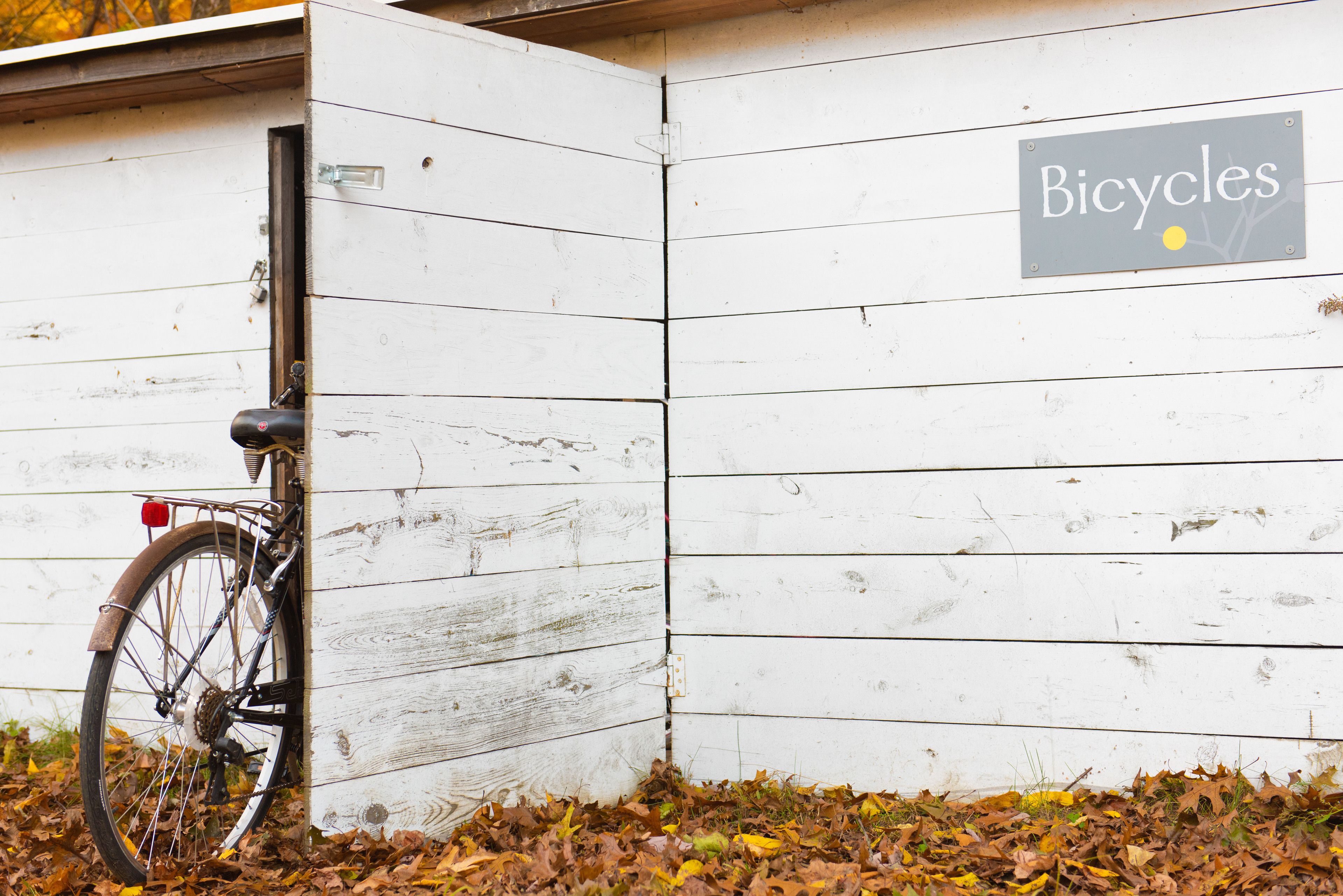 Una bicicleta apoyada en una pared de madera blanca con un letrero que dice "Bicycles".