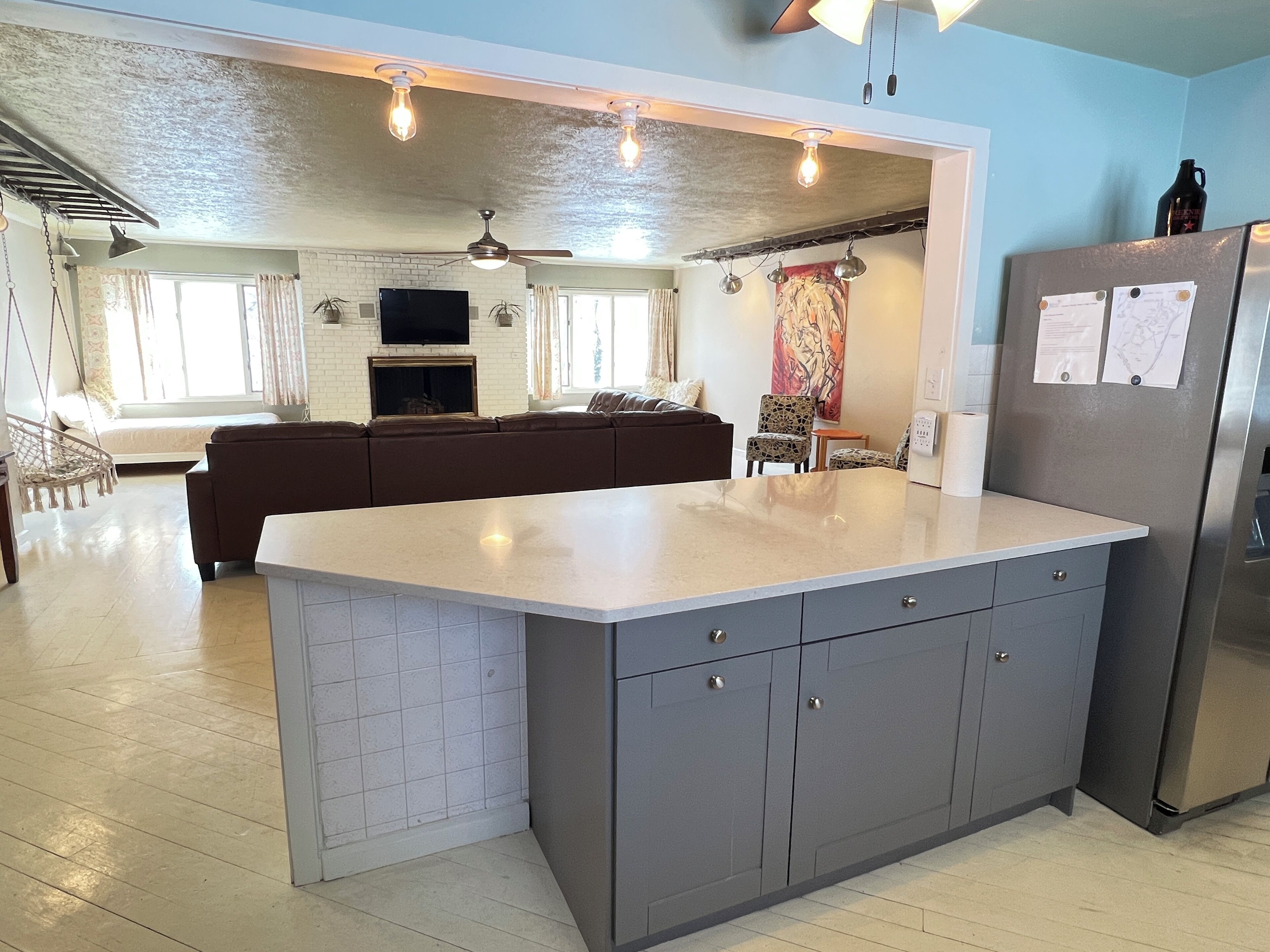 A modern kitchen with grey cabinets, a large island, and a built-in refrigerator.