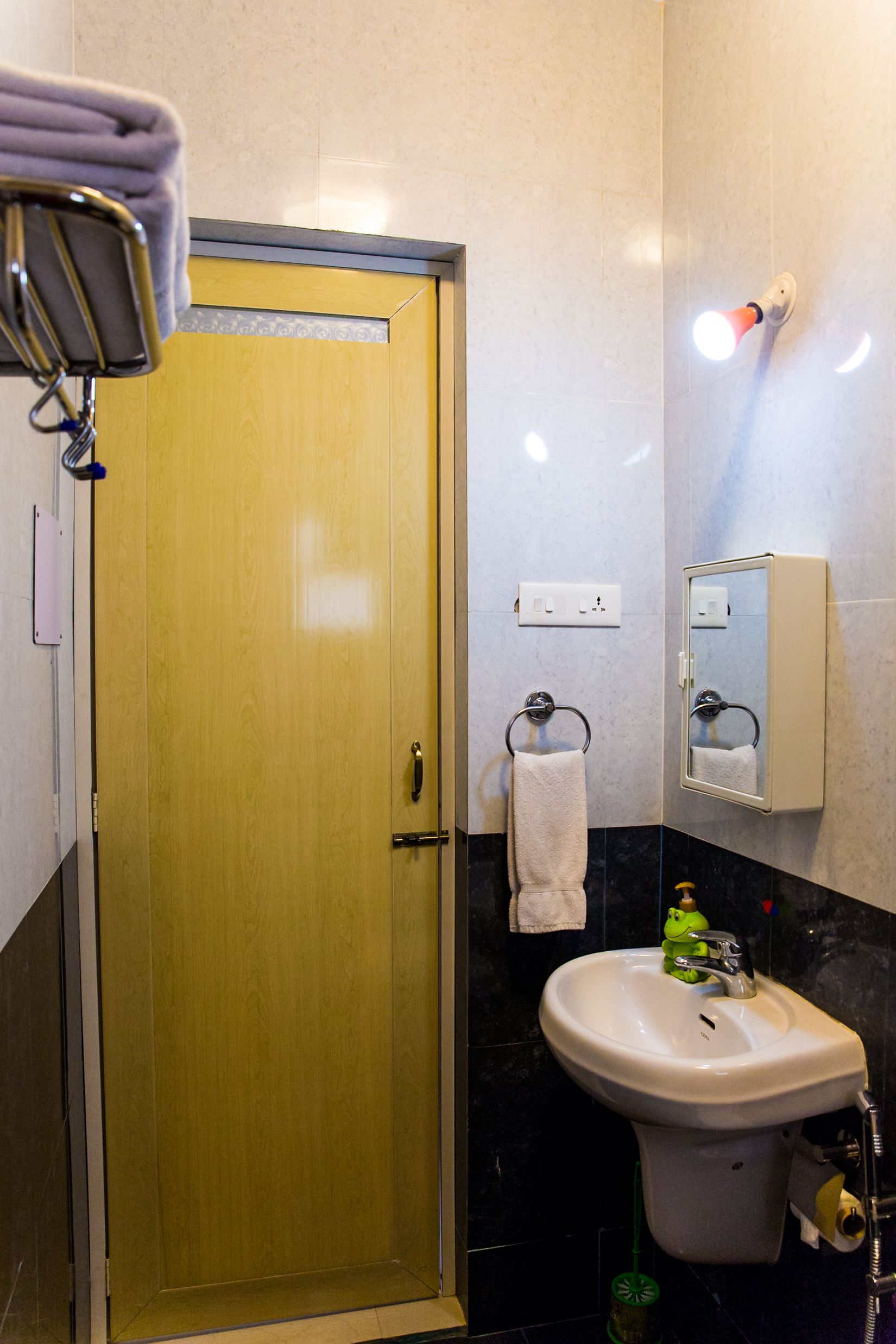 A bathroom with a wooden door, a white sink, a mirror, and a towel rack.