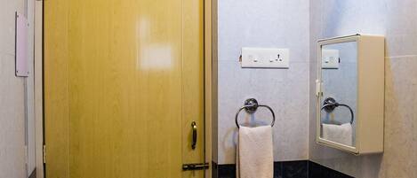 A bathroom with a wooden door, a white sink, a mirror, and a towel rack.